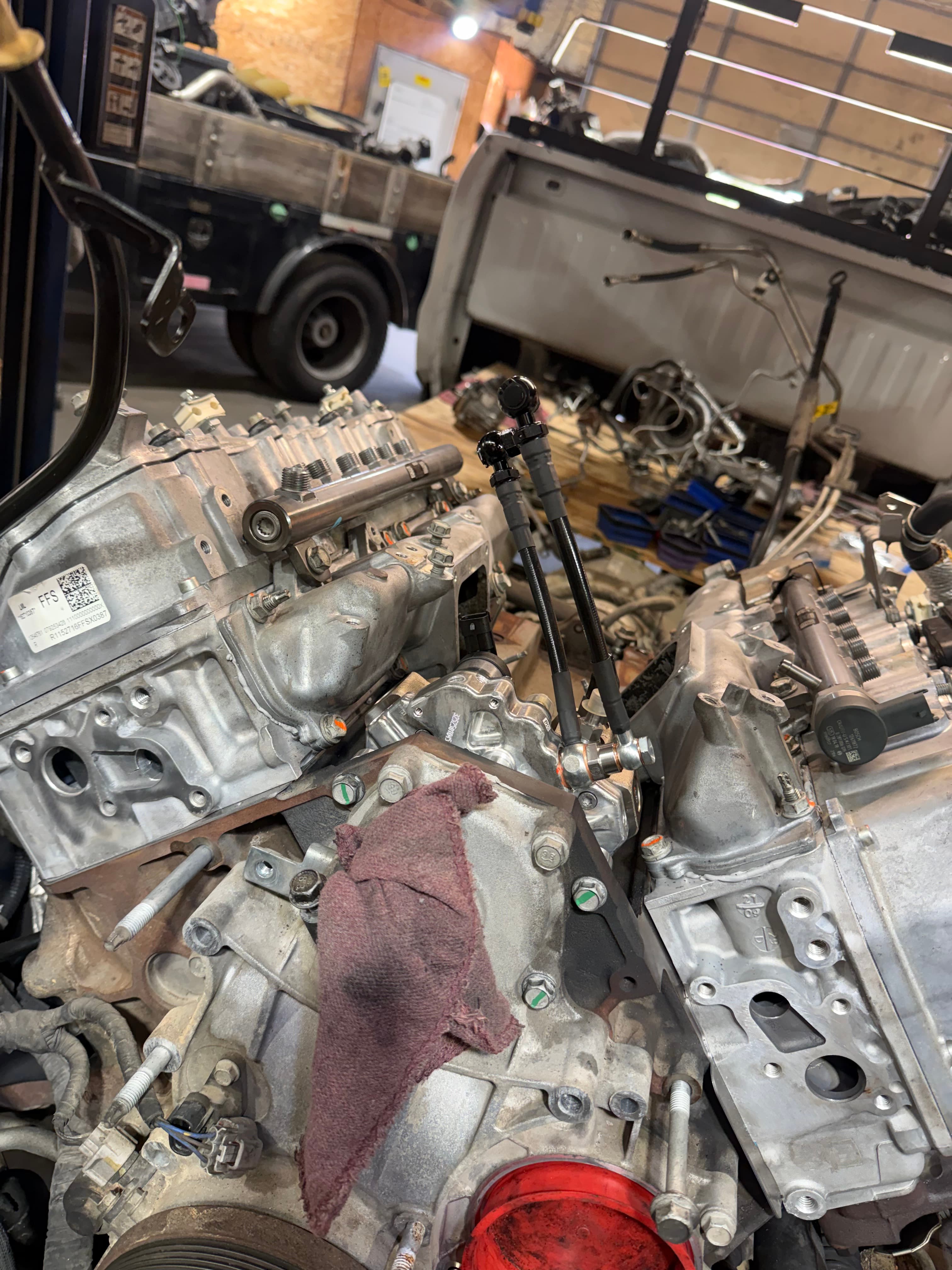 Close-up of a disassembled truck engine with fuel rails and components in a workshop.