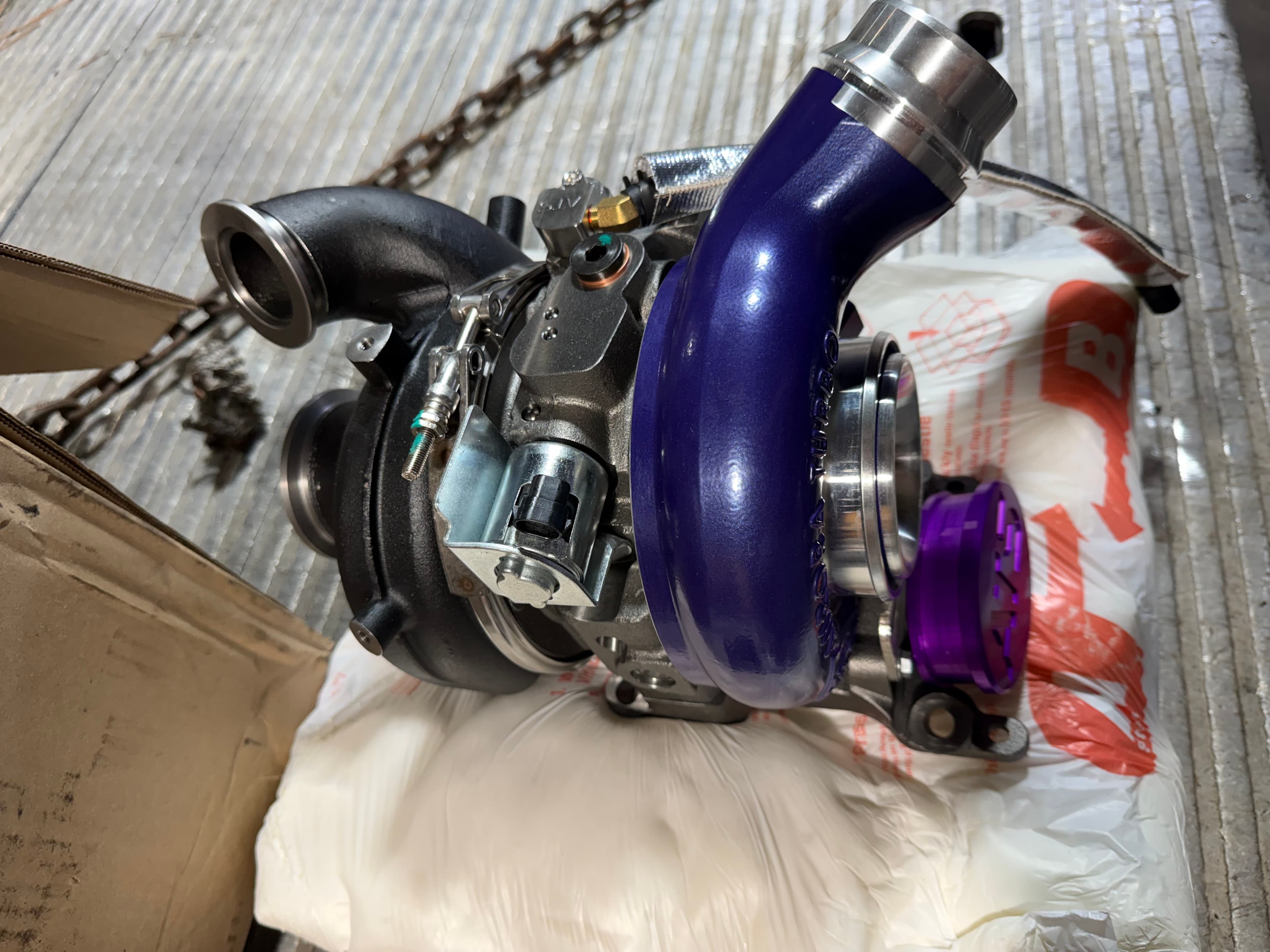 A high-performance turbocharger with a purple compressor housing and black exhaust components.